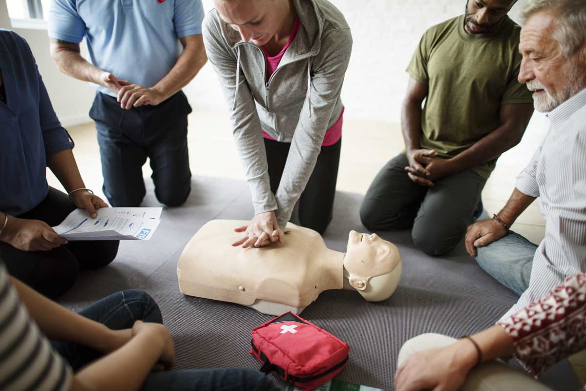People practicing CPR on mannequin during training session